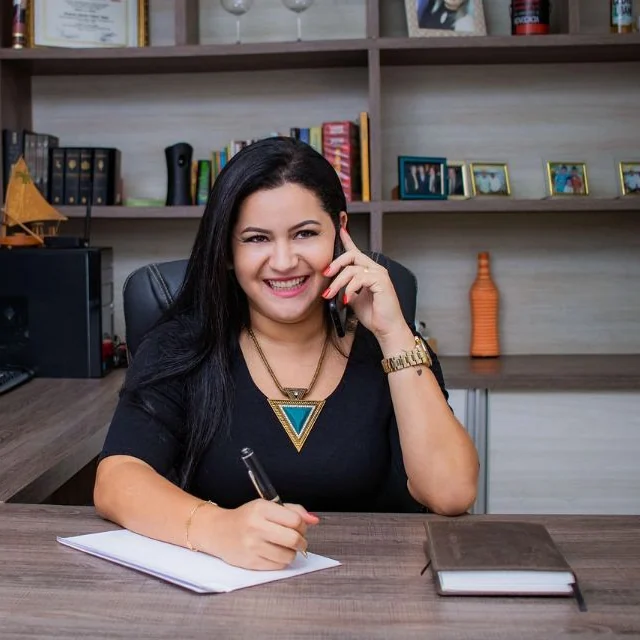 Advogada sorrindo ao telefone, anotando numa mesa de escritório