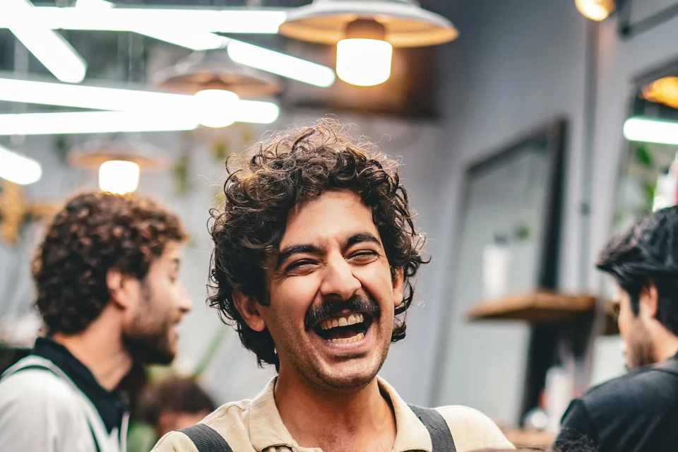 Barbeiro rindo com os clientes na barbearia