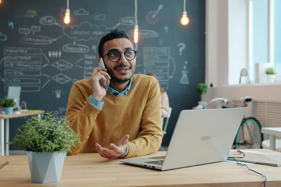 Profissional sorrindo ao telefone na mesa do escritório