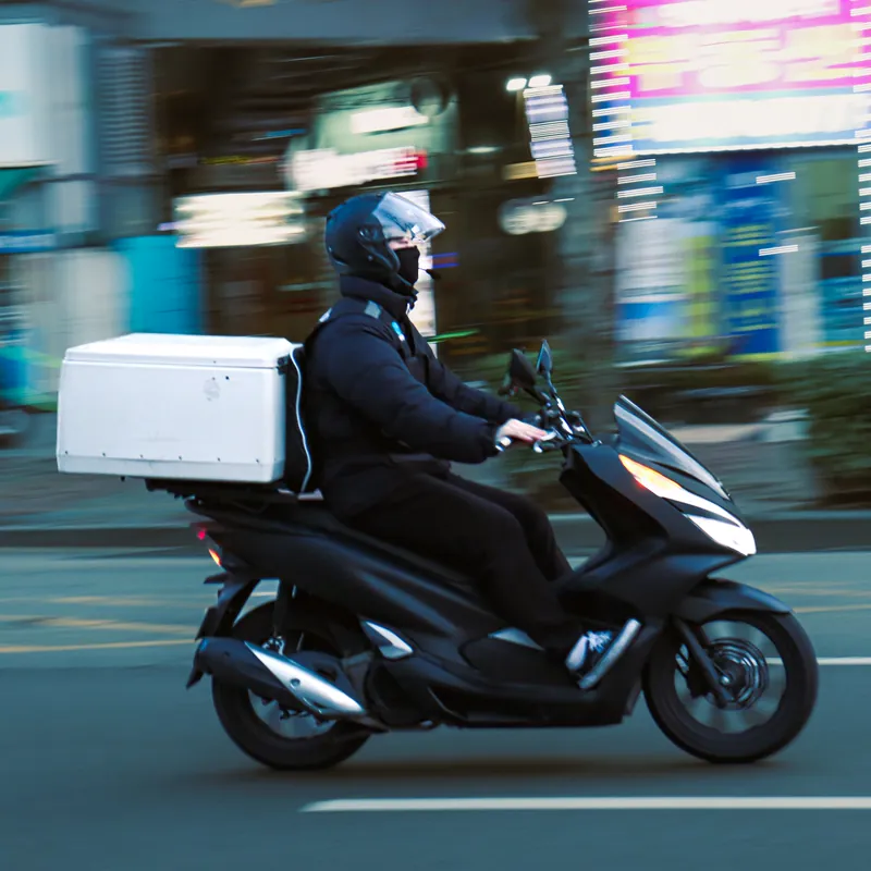 Entregador de moto com a caixa de entrega