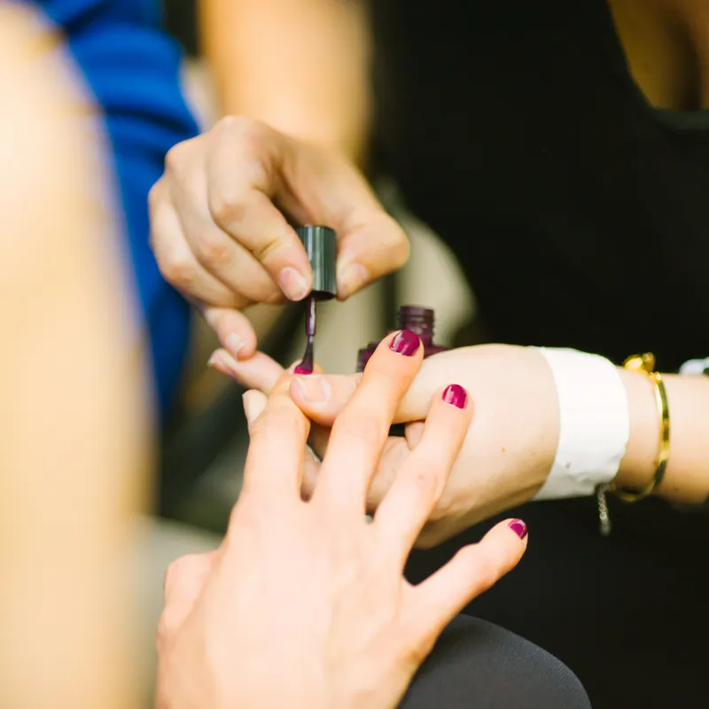 Manicure pintando as unhas de uma cliente